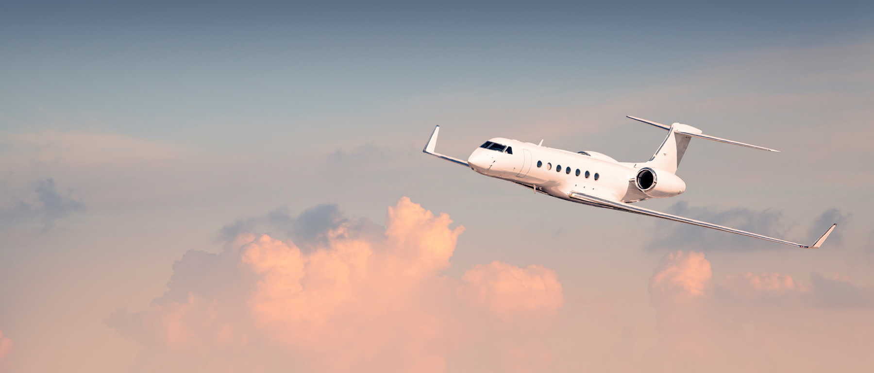 Business jet in flight against pink clouds